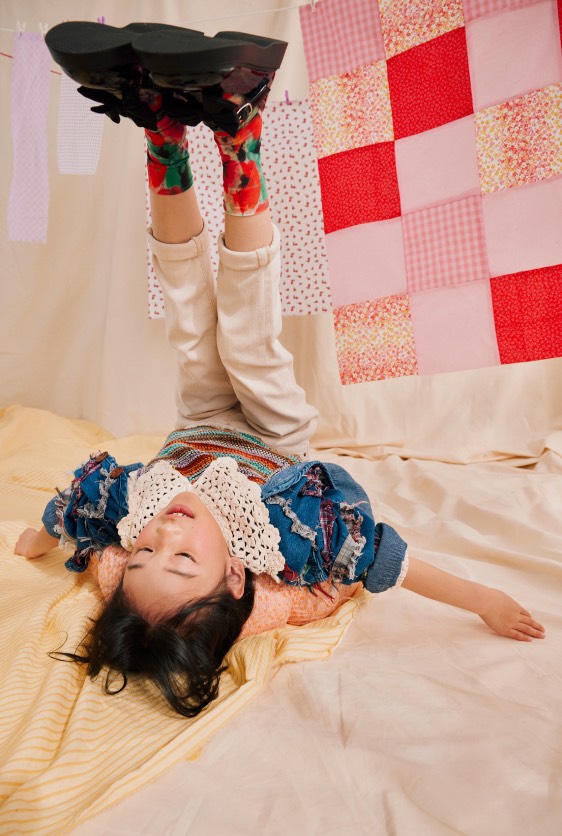 Child laying on a bed with feet in the air